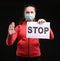 Teen girl in protective sterile medical mask on her face showing stop sign over black background