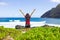 Teen girl raising arms in praise standing by ocean shore