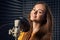 Teen girl in recording studio with mic over acoustic panel background