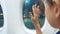 Teen girl says goodbye waving his hand at the window of the plane lifestyle aviation aircraft concept. Young girl looks
