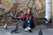 Teen girl sits near an old brick wall and feeding pigeons. Happy.