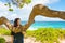 Teen girl sitting on bench under trees by ocean