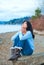 Teen girl sitting on boulder along lake shore praying