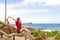 Teen girl sitting on fallen tree by tropical ocean