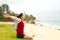 Teen girl sitting on grassy beach by ocean in Hawaii