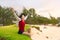 Teen girl sitting on grassy beach by ocean in Hawaii