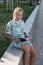 Teen girl sitting in the park and reading a book on a warm summer evening. Leisure of teenagers without a telephone