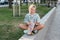 Teen girl sitting in the park with a skateboard in his hand. Leisure of teenagers without gadgets