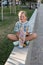 Teen girl sitting in the park with a skateboard in his hand. Leisure of teenagers without gadgets