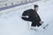 Teen girl sitting on snow tightening the laces on the skates