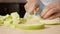 Teen girl is slowly cutting apple on small pieces, hands closeup.