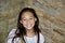 A Teen Girl Smiles with a Background of stone and brick.