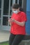 Teen girl texting standing outside school wearing surgical mask during COVID-19.