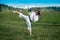 Teen girl training karate kata outdoors, performs the yoko geri kick