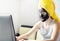 Teen girl using laptop computer sitting at home with black facial clay mask and yellow towel on head. Staying at home