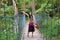 Teen girl on wooden hanging bridge in woods