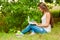 Teen girl works with the laptop on the grass