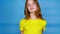 Teen girl in a yellow t-shirt is shrugs, turns her head and looking at camera, doesn\'t know