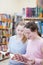 Teen girls in public library near shelves with books