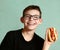 Teen handsome boy in myopia glasses with hot dog