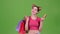 Teen holds shopping bags and a gold credit card. Green screen. Slow motion