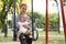 Teen nanny with cute little baby on swing. Space for text