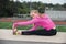 Teen in pink jacket activating hamstrings over field.