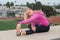 Teen in pink jacket stretching muscles over field.