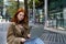 Teen redhead hipster girl using laptop on city urban street outdoors.