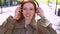 Teen redhead hipster girl wearing headphone listening music in the city.