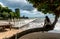 Teen sitting on tree looking at pier and beach