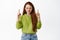 Teen sulking girl with red hair, grimacing and frowning angry, upset by something, pointing fingers up at top