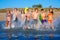 Teen surfers group running beach splashing