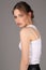 Teen in white singlet and skirt standing profile. Close up. Gray background