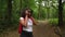 Teenage African American mixed race girl young woman hiking with red backpack and taking photographs with a camera in forest