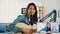 Teenage Asia girl influencer play guitar music use microphone record with smartphone for online audience listen at home. Female
