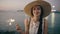 Teenage beautiful girl in hat with burn sparklers and smiling on the beach at sunset