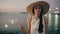 Teenage beautiful girl in hat with burn sparklers and smiling on the beach at sunset