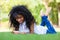 Teenage black girl using a phone, lying on the grass - African p