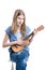 Teenage, blond girl in blue T-shirt is sitting and playing music on ukulele instrument