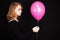 Teenage blond girl with pink balloon over black