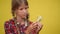 Teenage blurred girl examining white flower in light bulb at yellow background. Adolescent Caucasian serious teenager