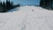 Teenage boy of 12 years in grey suit sliding on a snowboard from snow descent next sky lift. View from afar.