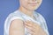 Teenage boy with adhesive bandage plaster on his arm after vaccination on blue background. Injection covid vaccine