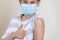 Teenage boy with adhesive bandage plaster on his arm after vaccination showing thumb up sign. Injection covid vaccine