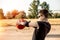 A teenage boy basketball player focused and pulled an orange basketball in his hands to the side of the ring, prepared to throw.