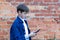 teenage boy in a blue shirt with a smartphone in his hands communicates with friends on social networks against the background of