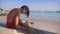 Teenage boy building sand castle on tropical beach