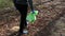 A teenage boy carries a green garbage bag after cleaning in the forest.