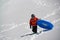 Teenage Boy carrying inflatable sledding tube up snowy hill in the mountains